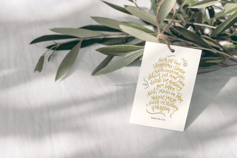 Blank paper gift tag, label mockup with rope and olive tree branch on white table background in sunlight. Summer sale, branding concept. Mediterranean design. Selective focus.